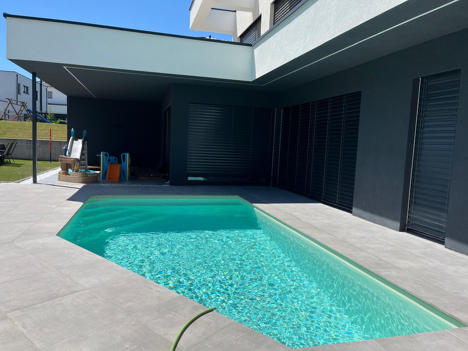Fertiggestellter Pool mit türkisem Wasser an modernem Wohnhaus