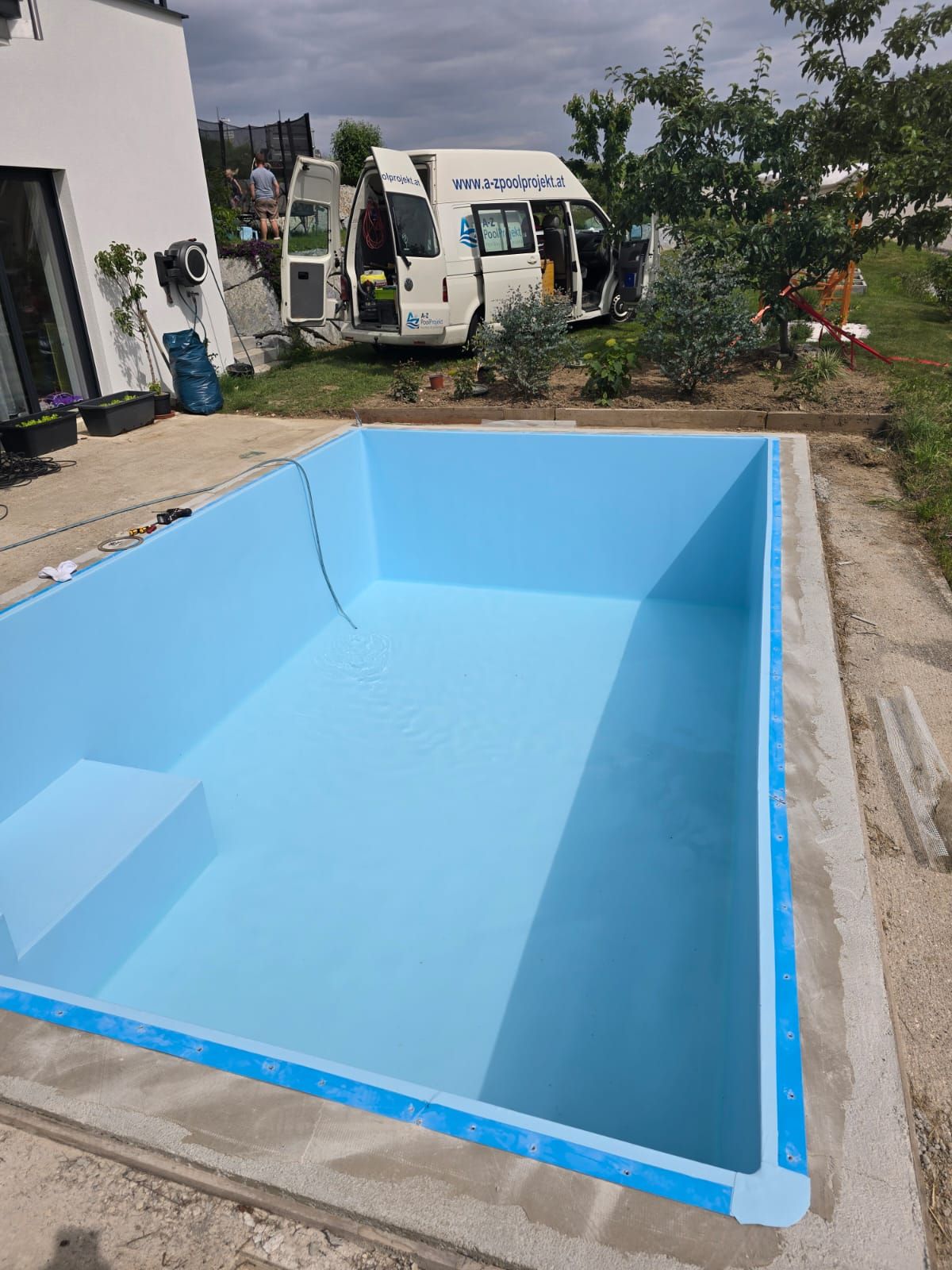Frisch verlegte hellblaue Poolfolie mit Servicefahrzeug im Hintergrund