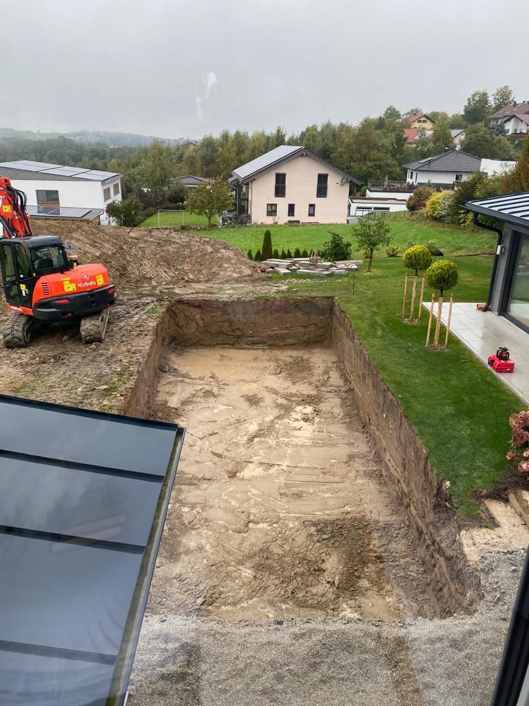 Bagger beim Aushub der Poolgrube im Garten